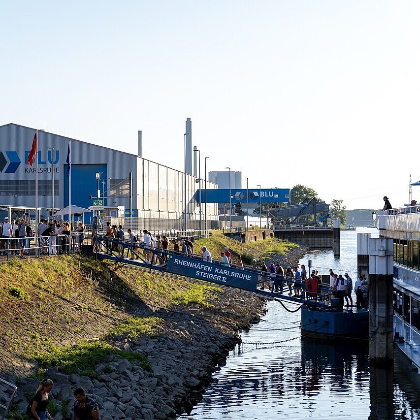 Besucherinnen und Besucher am Steg im Rheinhafen Karlsruhe auf dem Weg zu kostenlosen Rundfahrten mit dem Fahrgastschiff MS Karlsruhe.
